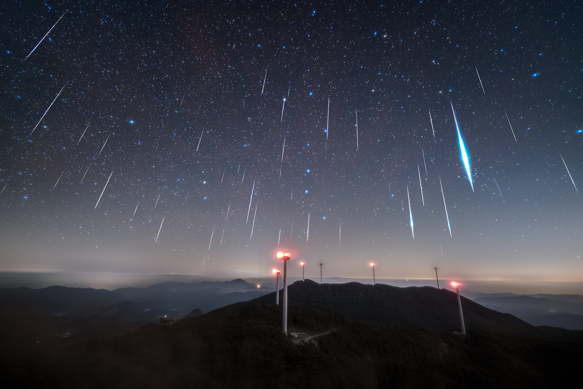 The Geminid meteor shower was once again reliable in 2025 is visible as many streaks of almost vertical lifht from a mountain top